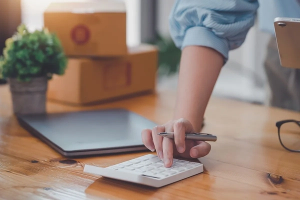 A person working with packaging is using a calculator