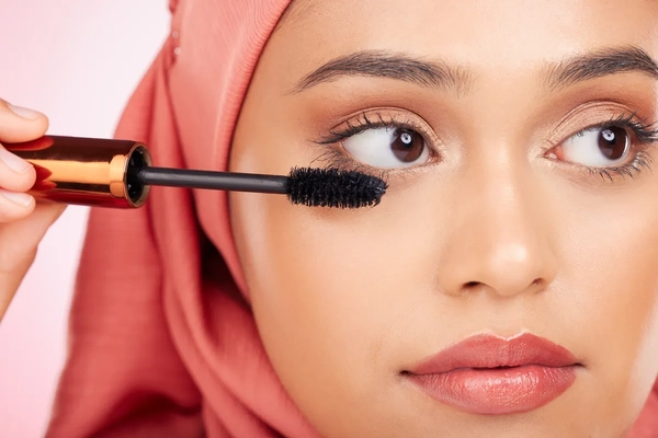 Image A woman putting mascara on her eyelashes.