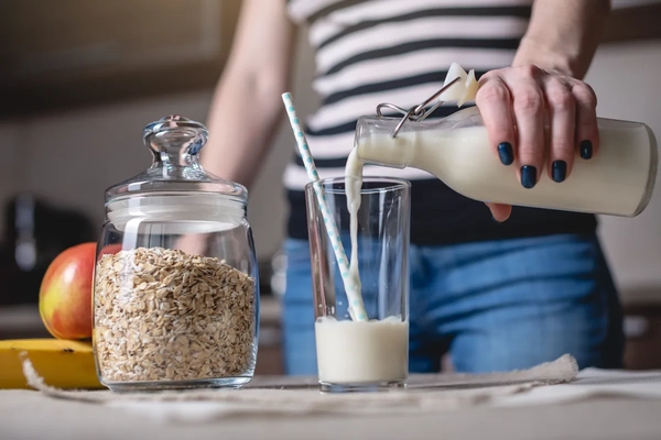 woman's hand pouring oat milk in a glass woman's hand pouring oat milk in a glass