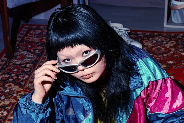 Image A woman wearing sunglasses, putting them down on her nose.
