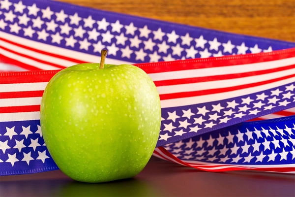 Green apple in front of American flag ribbon.
