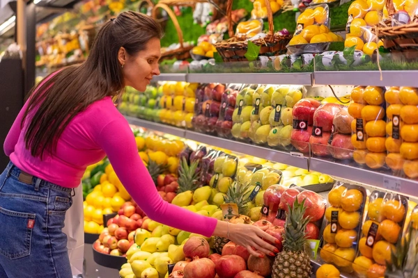 Image woman looks at fruit at supermarket