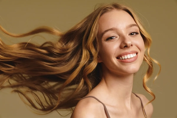 A woman smiling as her hair blows behind her.