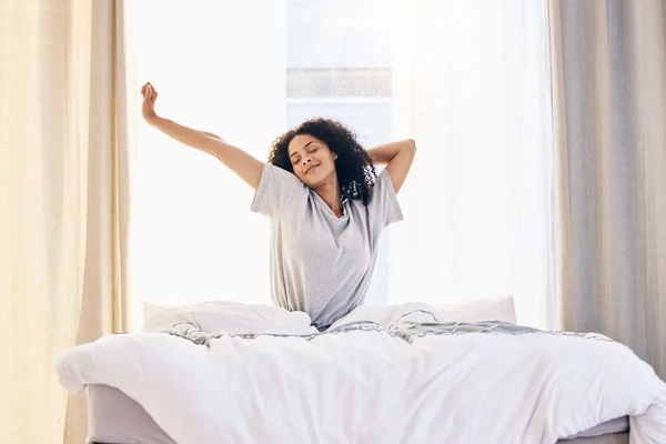 Morning stretching, black woman and wake up in home bedroom after sleeping or resting. 