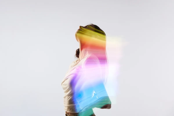 Image A woman with multi-color overlay in front of a white background.